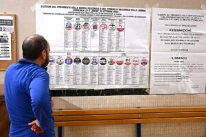 Cittadino guarda il cartellone con le liste elettorali