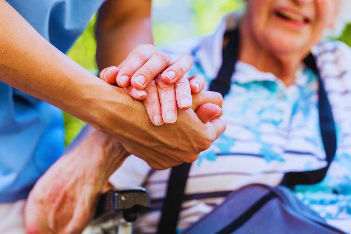 Caregiver stringe la mano ad anziana