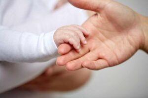 Un neonato stinge la mano alla madre