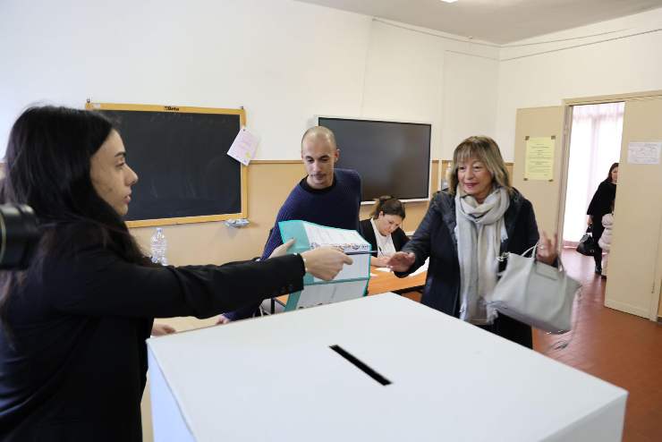 una persona si reca a depositare la scheda del voto al seggio