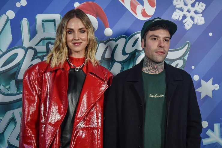 chiara e fedez in posta di fronte a un cartellone di un evento di natale