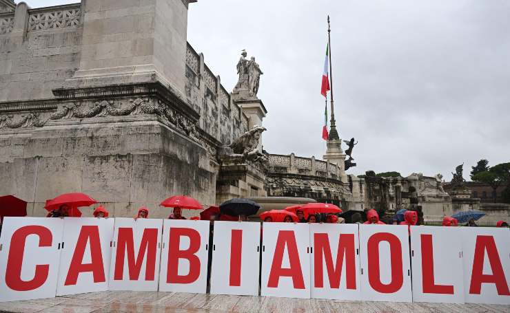 Un gruppo con un cartello con scritto cambiamola