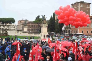 persone con giacche e ombrelli rossi scioperano