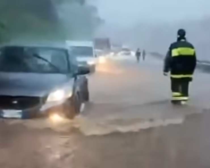 un pompiere in strada con l'acqua che impedisce alle auto di muoversi