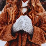 ragazza coperta con guanti e cappotto sotto la neve