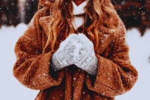 ragazza coperta con guanti e cappotto sotto la neve