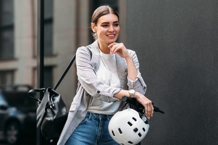 Una donna sta per mettersi il casco sul monopattino elettrico