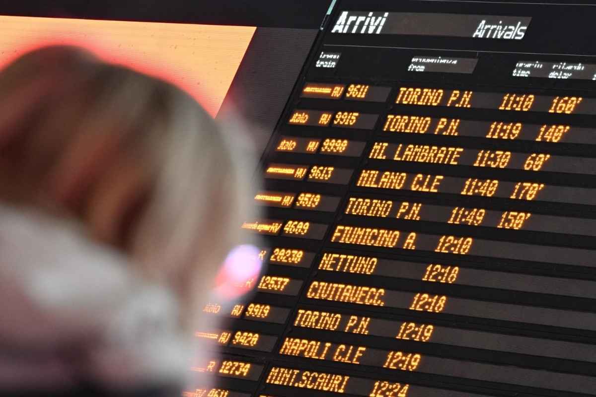 Donna che aspetta il proprio treno e controlla il tabellone