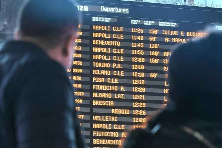 Donna che aspetta il proprio treno e controlla il tabellone