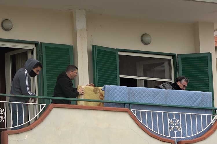 Operai sopra il balcone di un'abitazione che trasportano un materasso