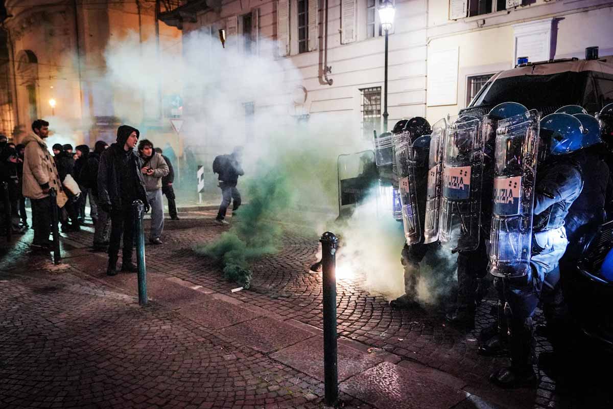 alcune persone fronteggiano la polizia in assetto antisommossa