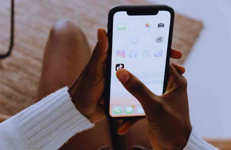 ragazza tiene smartphone e clicca su icona tiktok