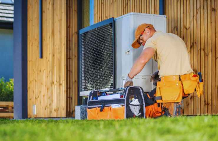 un operaio che lavora su una pompa di calore con la cassetta degli attrezzi vicina