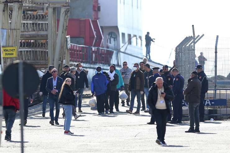 migranti che camminano vicino all'imbarcazione