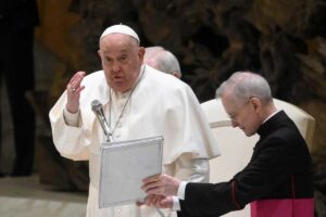 papa francesco parla al microfono con un vescovo al suo fianco