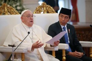 papa francesco seduto che parla durante una conferenza