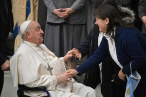 papa francesco seduto da le mani a una signora