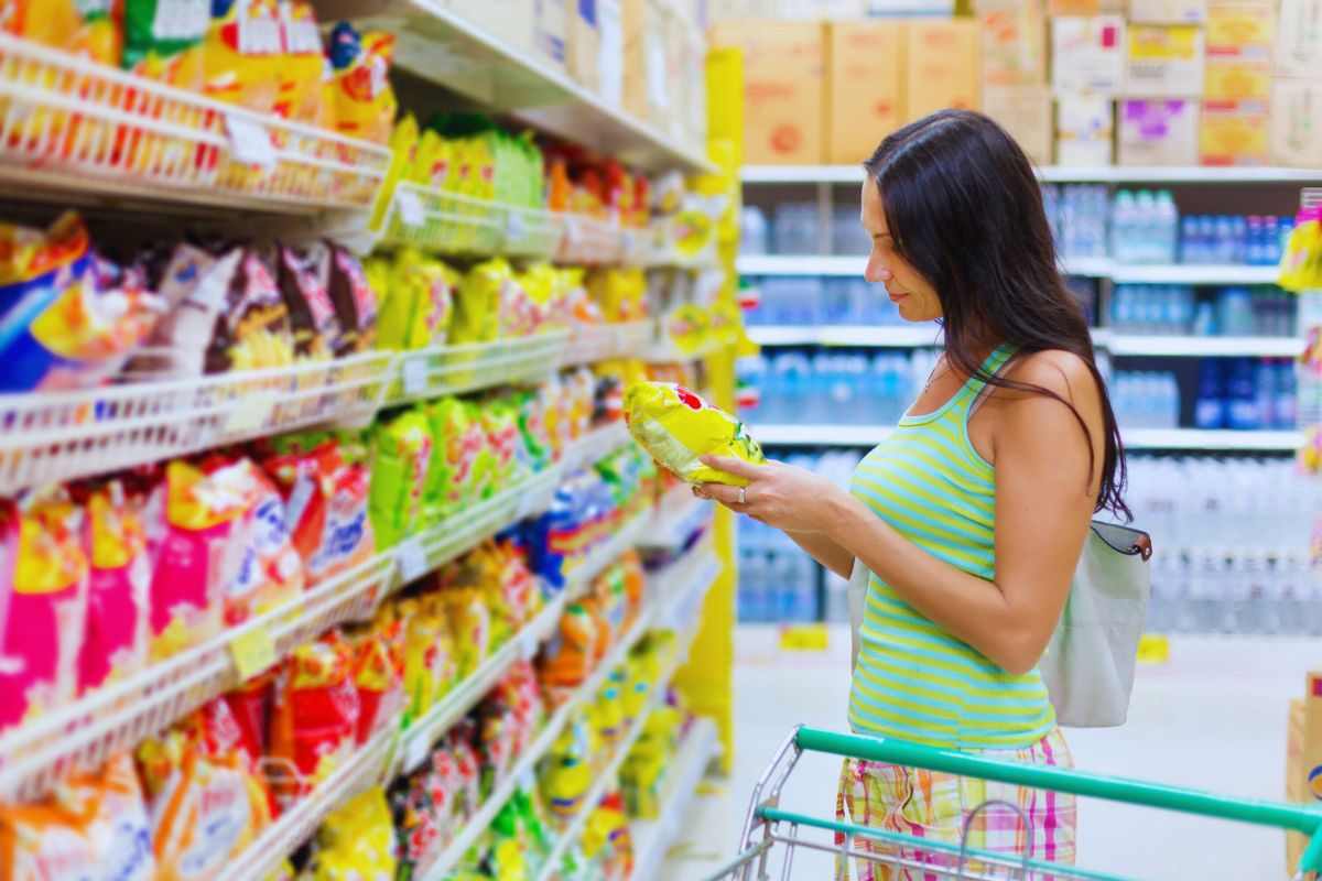 ragazza sceglie pacchetto di patatine al supermercato