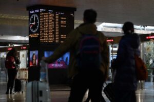 delle persone in stazione di fronte ai tabelloni con gli orari