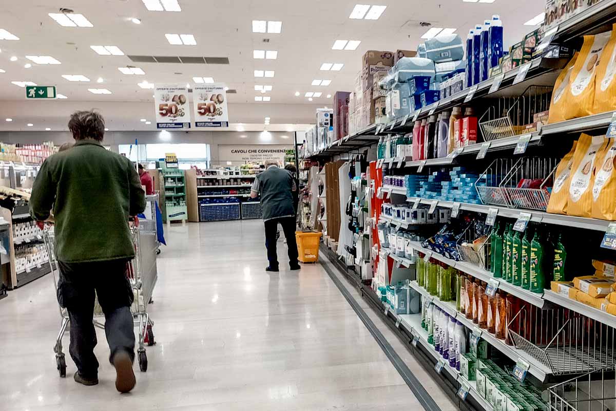 un uomo spinge il carrello nel corridoio di un supermercato