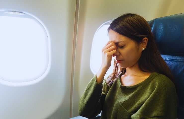 ragazza spaventata per la paura dell'aereo si tiene la testa