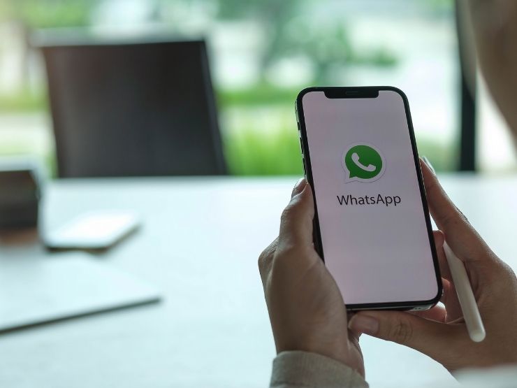 Icona di Whatsapp sullo smartphone di una ragazza seduta al tavolo in ufficio