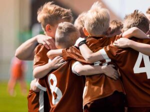 Un gruppo di bambini si abbraccia durante una partita di calcio