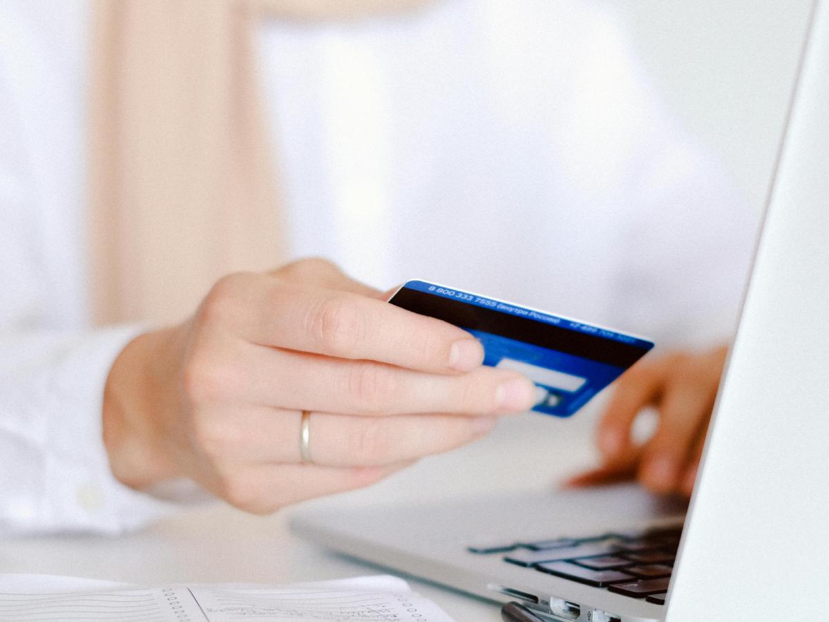 Acquisti online: una donna contempla una carta di credito