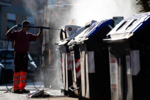 un uomo che pulisce i secchi della spazzatura