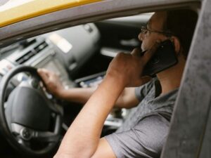 Uomo al volante con un telefono all'orecchio